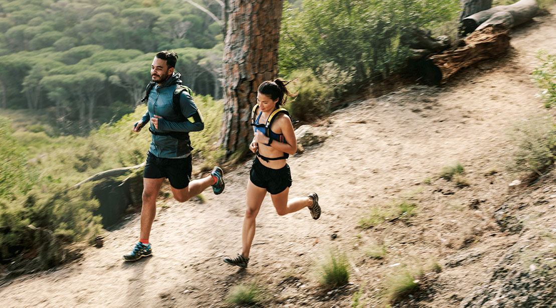 Home 16 Male and female trail runners running outdoors on a forest trail